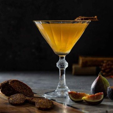 Fig Vodka Martini in a vintage cocktail glass next to fresh fig and vegan fig salami