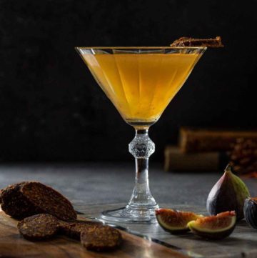 Fig Vodka Martini in a vintage cocktail glass next to fresh fig and vegan fig salami