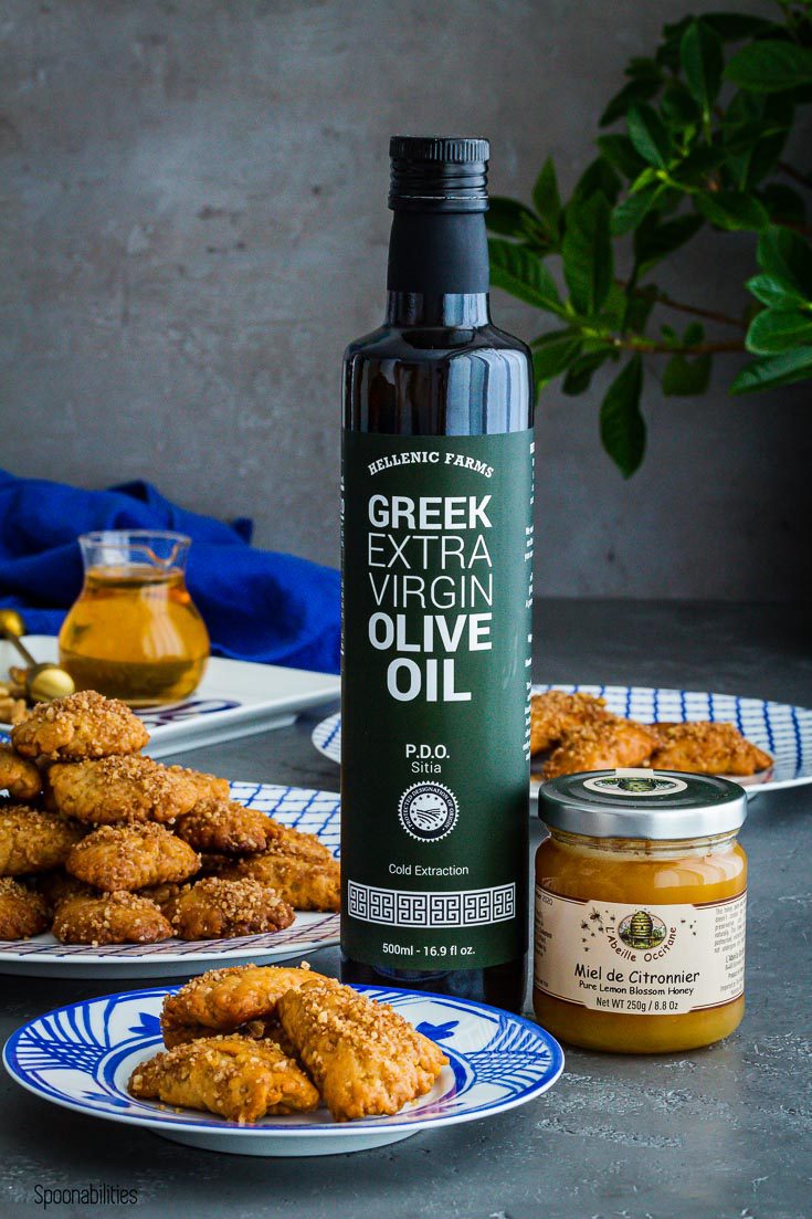 A small plate with three cookies and next to the plate a large bottle of Hellenic Farms extra virgin olive oil PDO Sitia and a jar of French honey. Spoonabilities.com