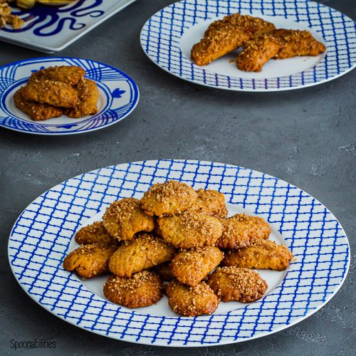 several Melomakarona Greek Honey Christmas Cookies on a white and blue plate. Spoonabilities.com