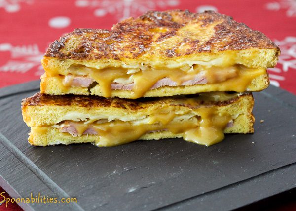 two slices of Monte Cristo sandwiches stacked on top of each other with cheese dripping out the side. Spoonabilities
