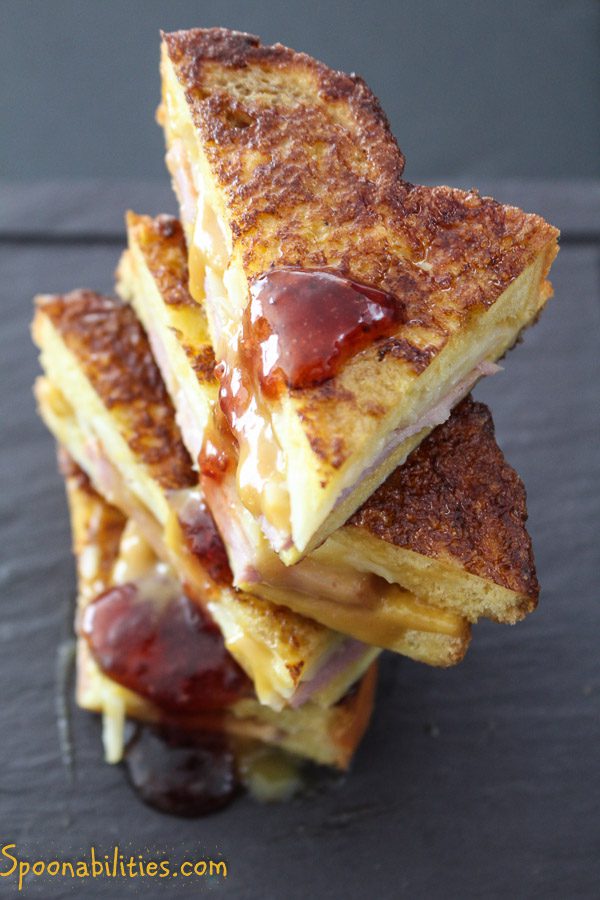 four slices of Monte Cristo sandwiches stacked on top of each other with strawberry jam dripping down the side. Spoonabilities