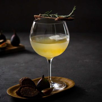 Cocktail of rosemary Gin, Elderflower & Fig Tonic on a small wood tray