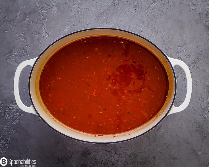 White cast-iron pot with the sauteed veggies, San Marzano tomatoes and chicken stock. Recipe at Spoonabilities.com