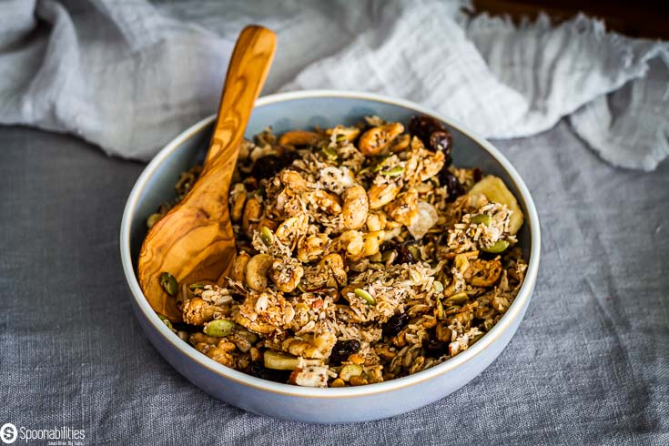 Light blue bowl with vegan granola recipe with a olive oil spoon in the bowl. Recipe at Spoonabilities.com