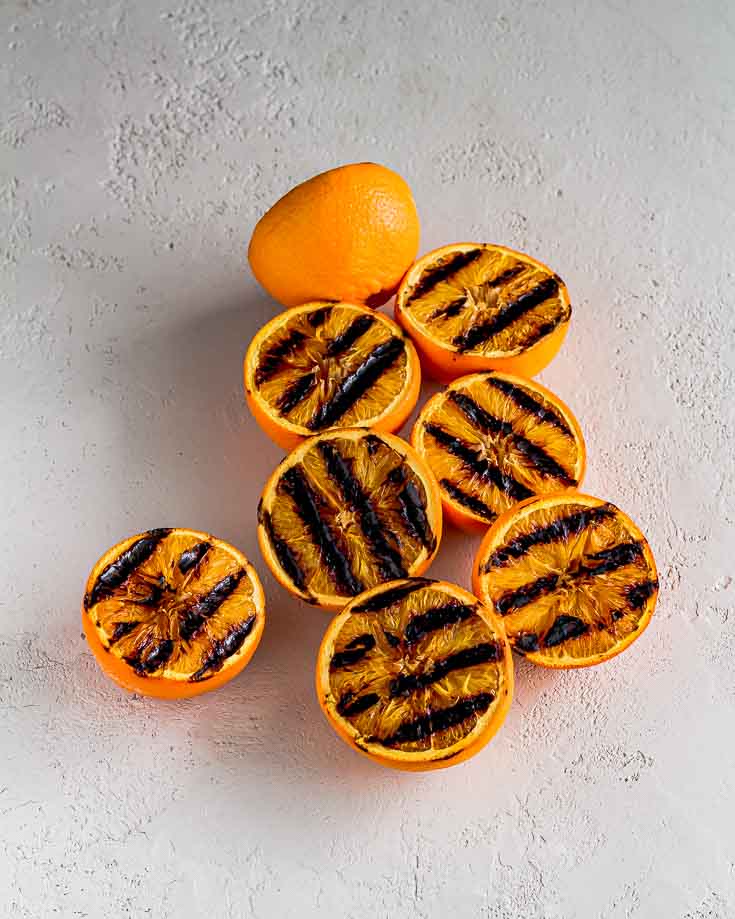 eight half of grilled oranges in a white surface. Recipe at Spoonabilities.com