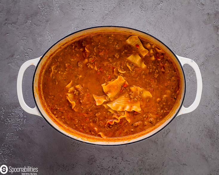 Easy one-pot lasagna soup ready in a white cast-iron pot. Recipe at Spoonabilities.com