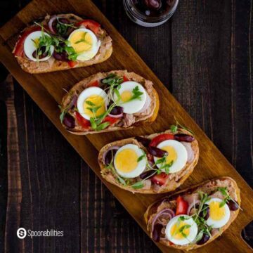 Square photo with an overhead shoot for the Tuna Nicoise Crostini using Anise Marinated Kalamata Olives. Available at Spoonabilities.com