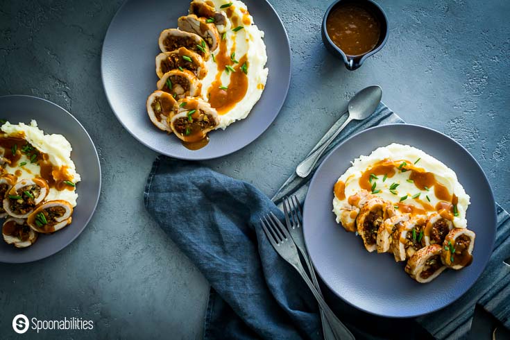 Three blue plates with stuffed pork chops and mashed potatoes. Recipe at Spoonabilities.com