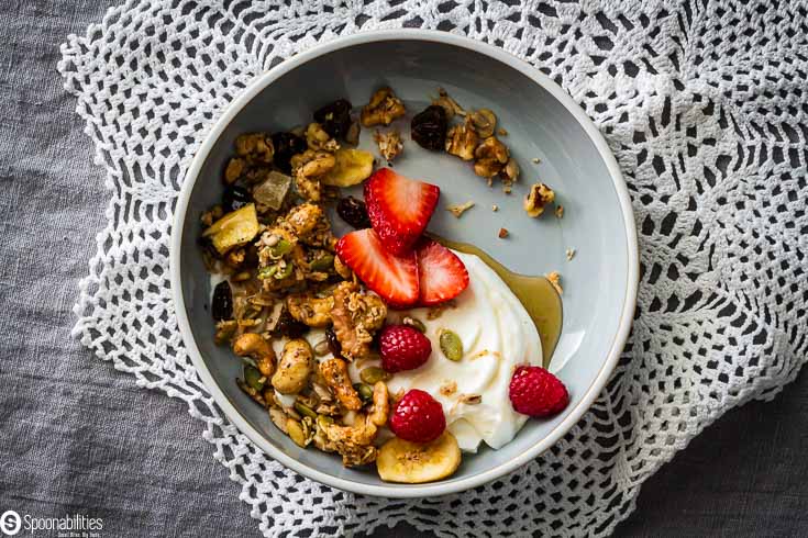 Overhead photo with a bowl of granola, berries, yogurt and maple syrup. Recipe at Spoonabilities.com