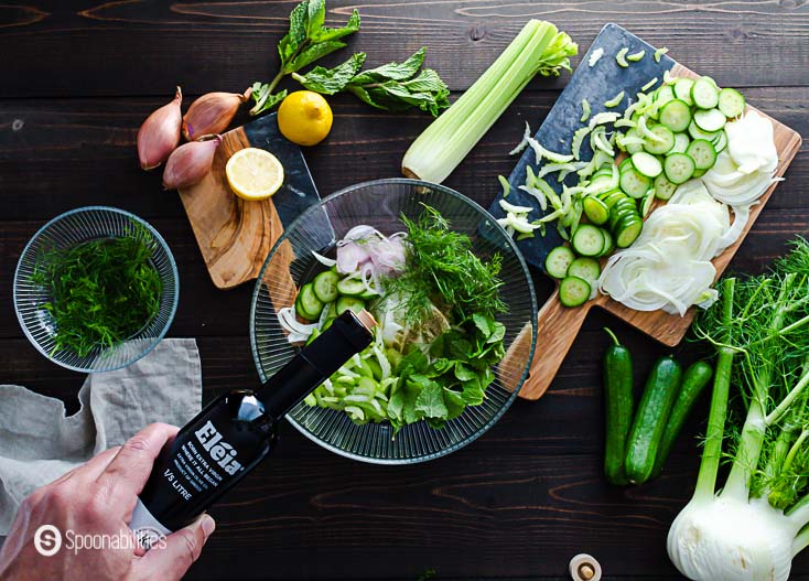 The slaw ingredients in a glass bowl and adding the Eleia extra virgin olive oil. Recipe at Spoonabilities.com