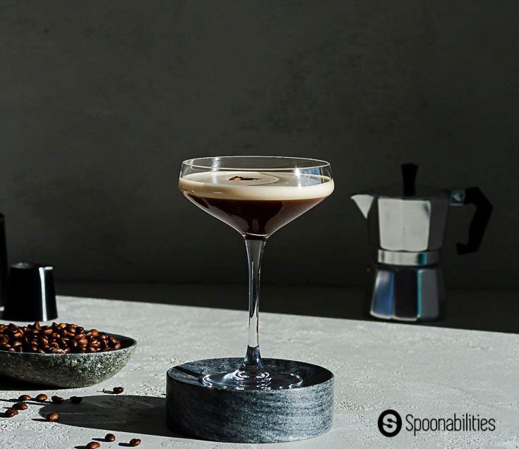 side view of an espresso martini sitting on a dark gray marble pedestal