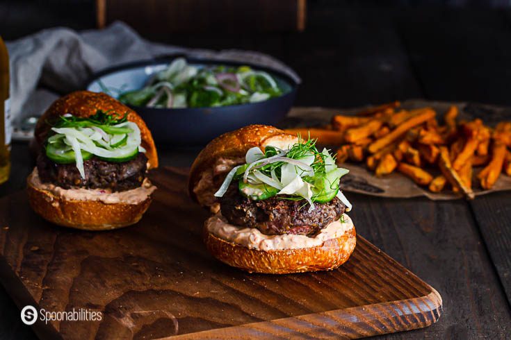 Two lamb burger in a wooden cutting board. In the background some sweet potato fries. Recipe at Spoonabilities.com