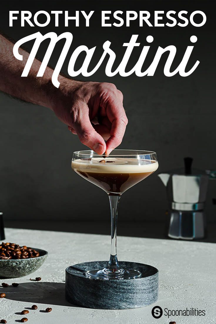 hand placing 3 espresso beans as a garnish on top of a frothy espresso martini