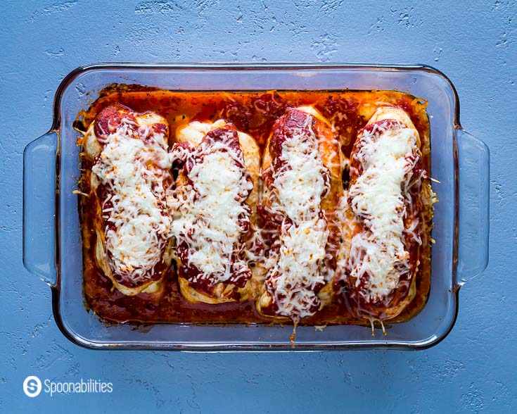 Stuffed Chicken in a glass baking dish, right out of the oven with melted mozzarella cheese and pizza sauce on top. Recipe at Spoonabilities.com