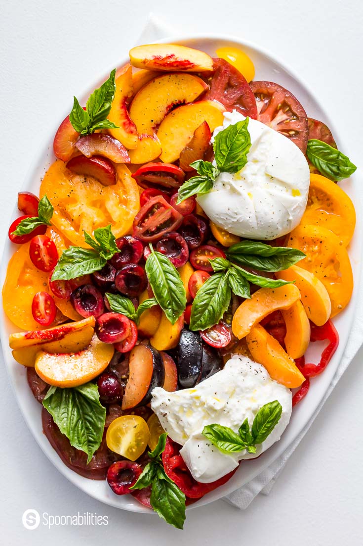 Overhead photo of the Stone Fruit Caprese salad presented in a oval white serving plate. Recipe at Spoonabilities.com