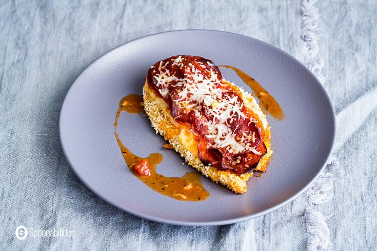 Chicken Parmesan topped with pepperonis, melted mozzarella cheese, and pizza sauce in a round grey plate. Recipe at Spoonabilities.com