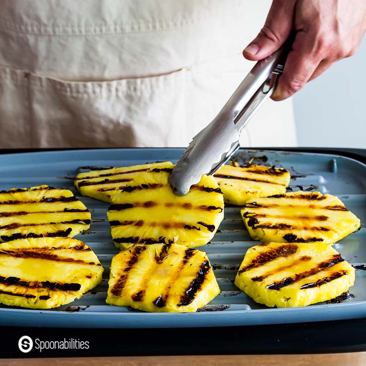 Grilling eight pineapple rings in a electric grill. Recipe at Spoonabilities.com