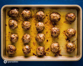 Baking tray with eighteen baked lamb meatballs mixed with fig salami. Recipe at Spoonabilities.com