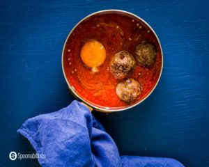 personal serving saucepan with the Easy shakshuka before go to the oven. This saucepan has three lamb meatballs with one egg. Recipe at Spoonabilities.com