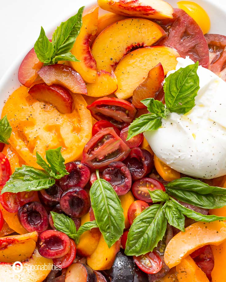 Tight close up of the caprese salad with fresh cherries, heirloom tomatoes, peaches, apricot, plum, and cherry tomatoes. Recipe at Spoonabilities.com