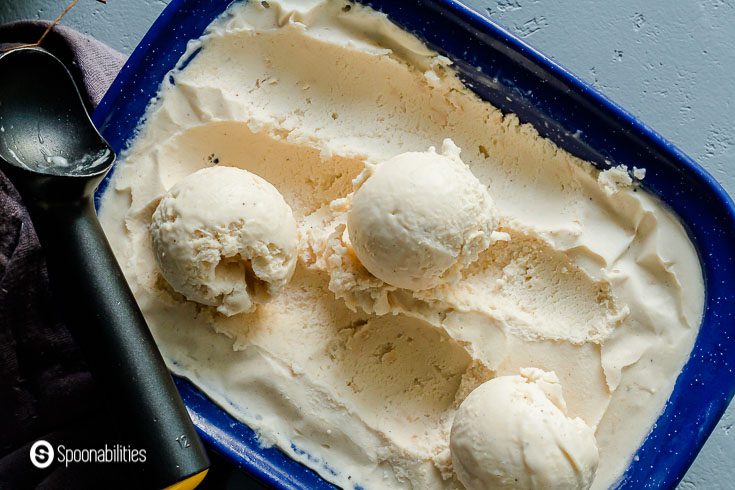 Close up of the Coconut cream ice cream in a blue container. Three ice cream scoops out on top. Recipe at Spoonabilities.com