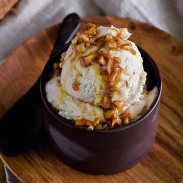 Close up photo of a Coconut Ice Cream with Hazelnut Brown Butter Sage Sauce on top of the ice cream and in the back of the photo in a small bowl. Recipe at Spoonabilities.com