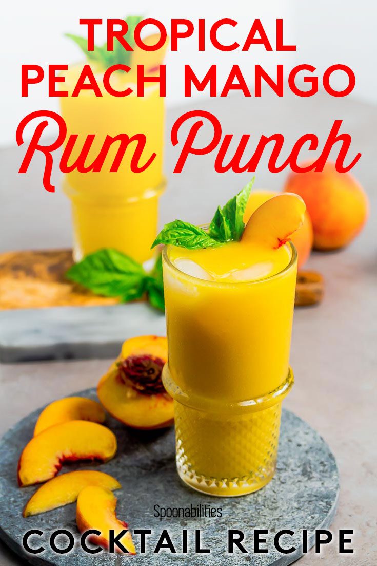 Pinterest photo with the Tropical Peach Mango Rum Punch on top of a marble round tray. Next to the glass is a half a peach with 4 slices. Recipe at Spoonabilities.com