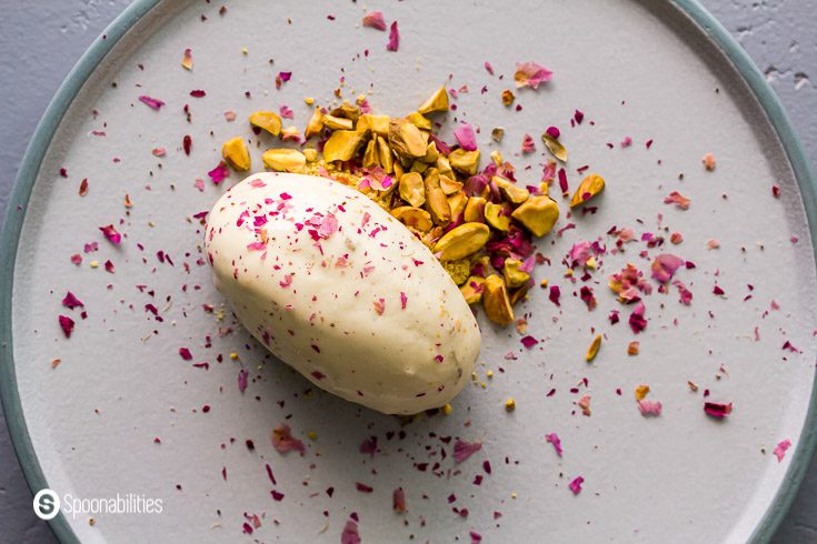 Ice cream plated like restaurant with one quenelle persian ice cream on top of chopped pistachios and crushed edible rose petals. Recipe at Spoonabilities.com