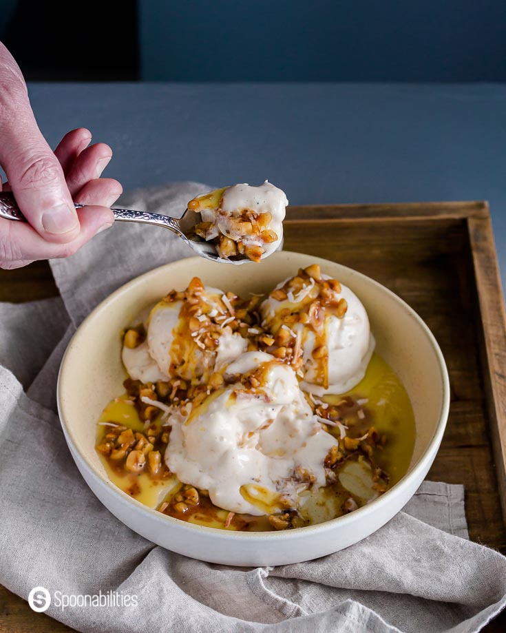 A bowl with the ice cream and the Hazelnut Brown Butter Sage Sauce. A hand spooning out some of the ice cream. Recipe at Spoonabilities.com