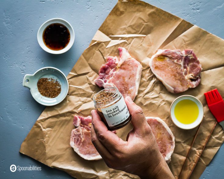 Seasoning the four pork chops with Greek sea salt smoked in beechwood. Recipe at Spoonabilities.com