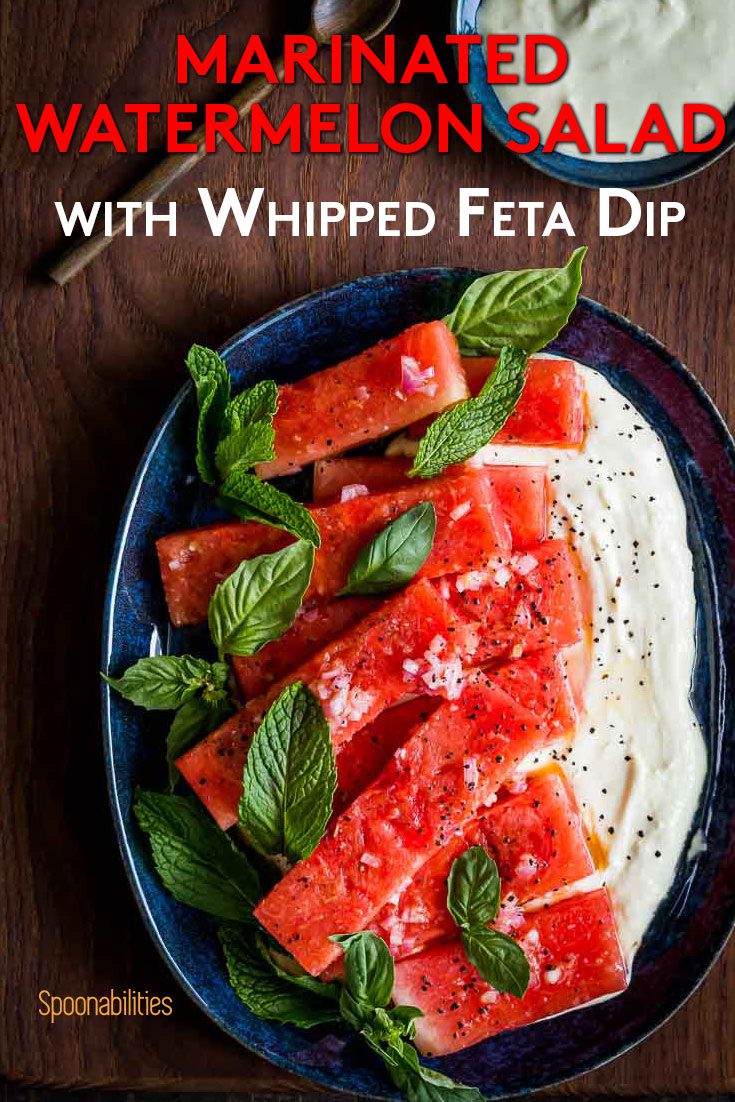 An oval blue plate with ten pieces of Marinated Watermelon Salad with Feta Dip and garnished with fresh herbs. Recipe at Spoonabilities.com