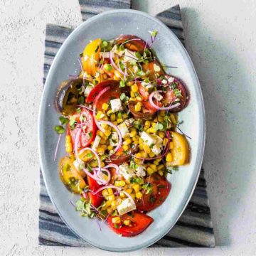 An oval pewter finish plate with Simple Heirloom Tomato Salad. Recipe at Spoonabilities.com