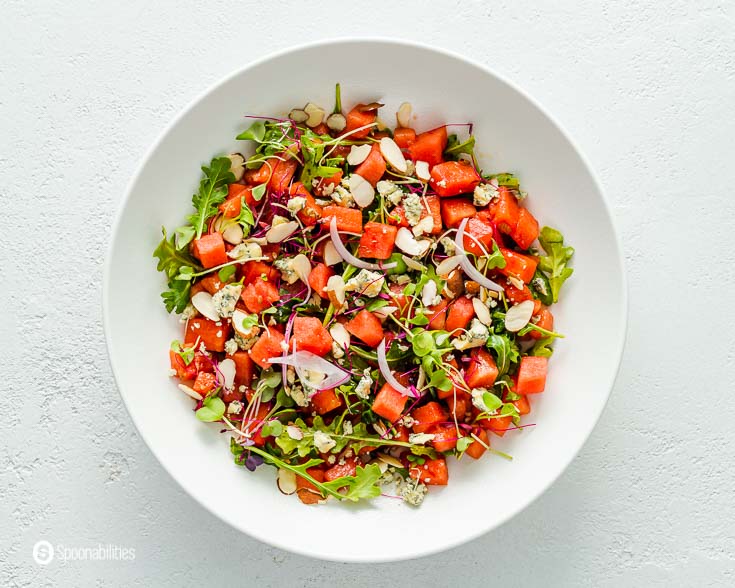 White round plate with a watermelon arugula salad. Recipe at Spoonabilities.com