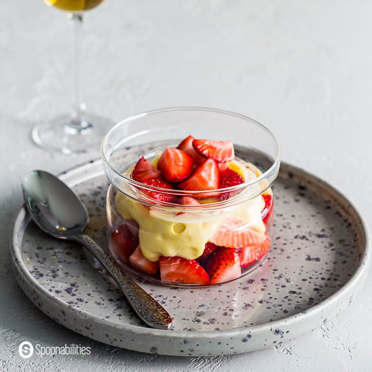 Flat grey plate with a glass bowl with strawberries and Zabaglione. 