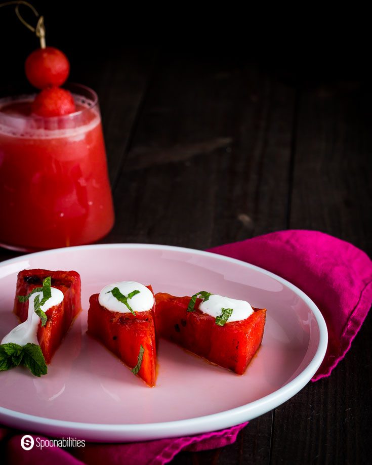 Close up photo of the round pink plate with three wedges of grilled watermelon. Recipe at Spoonabilities.com