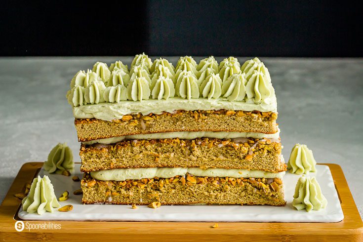 Close of of the whole pistachio tiramisu cake on top of a wooden/porcelain plate. Recipe at Spoonabilities.com