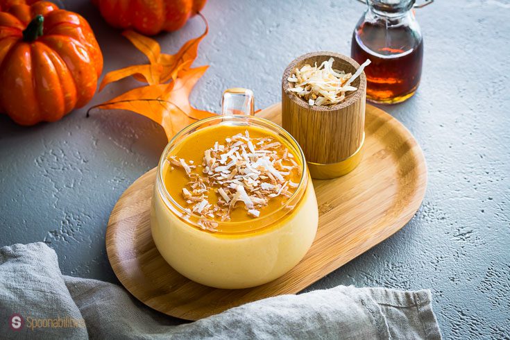 A Glass coffee cup filled with a delicious panna cotta made out of pumpkin, spices, maple syrup, and garnished with toasted coconut flakes. Recipe at Sponabilities.com