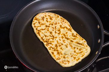 Frying the second side of the naan bread in a skillet, you already can see the char marks. Recipe at Spoonabilities.com