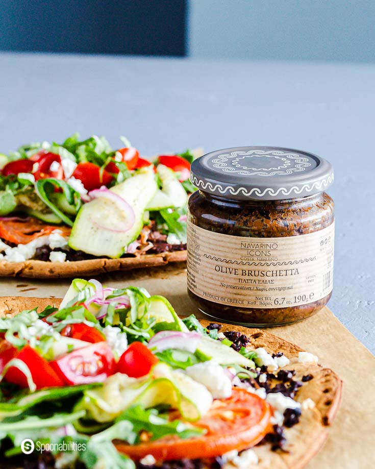 A jar of Olive Bruschetta from Navarino Icons between two veggie pizza. Recipe at Spoonabilities.com