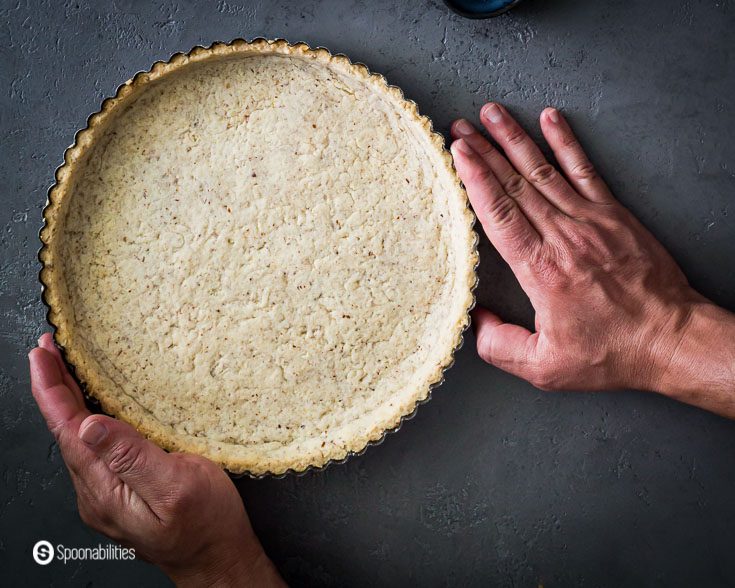 Two hands holding the Par Baked Pie Crust after came out of the oven. Find out in the post what is par baked crust. Recipe at Spoonabilities.com