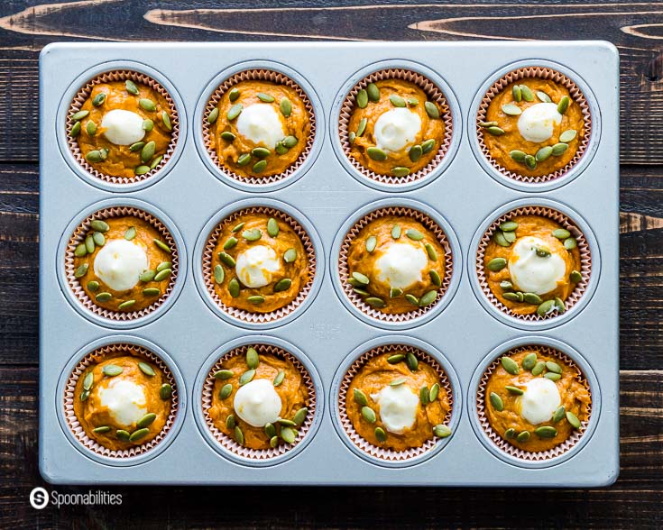 Muffins tin with twelve pumpkin cream cheese muffins with pumpkin seeds. This a Starbucks copycat recipe. Recipe at Spoonabilities.com