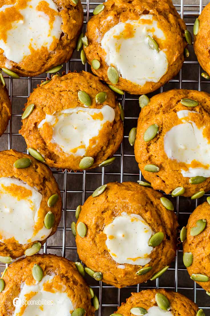 Close up from overhead with seven pumpkin muffins with cream cheese filling and toasted pumpkin seeds. Recipe at Spoonabilities.com