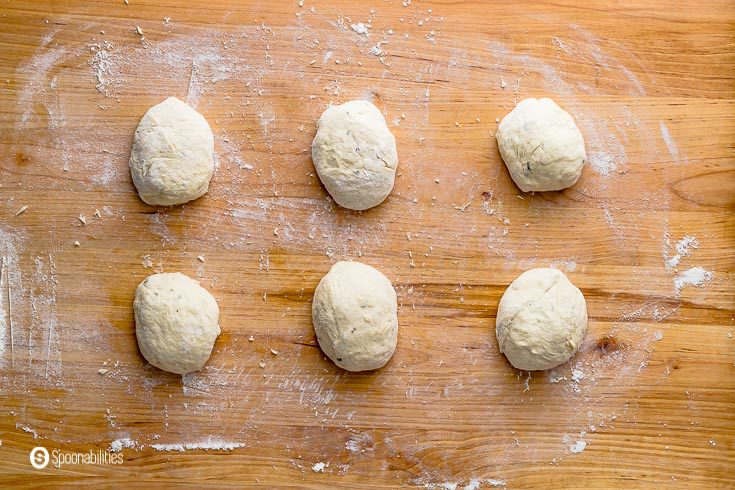 Six dough balls in a wooden board before getting shape into the traditional naan bread shape. Recipe at Spoonabilities.com