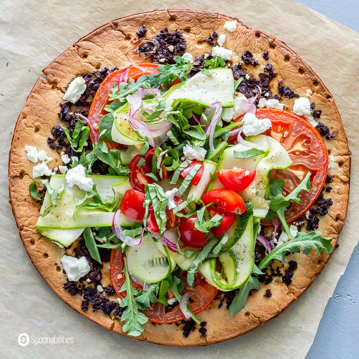 Close up of one veggie pizza with cauliflower pizza crust, Olive Bruschetta, and topped with a lot fresh vegetables. More about this recipe at Spoonabilities.com