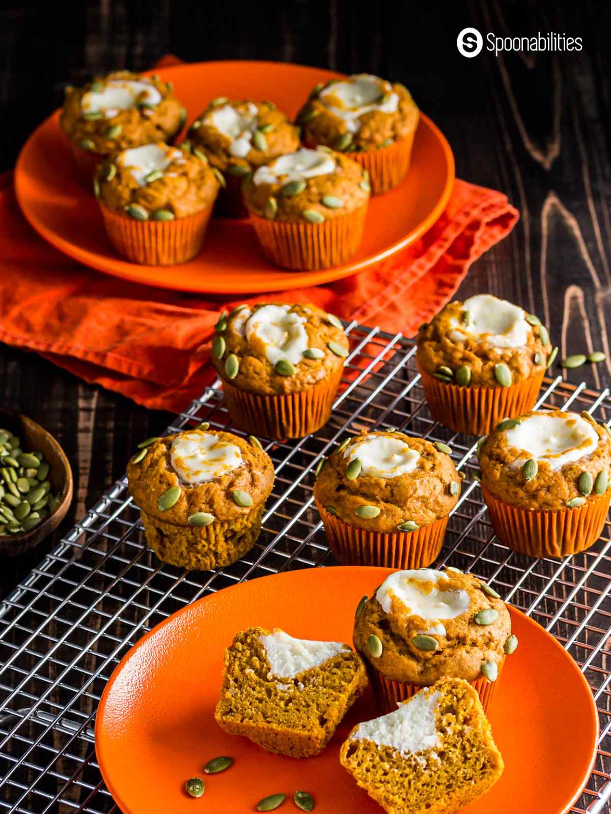 Two orange plates and cooling rack with pumpkin muffins on top