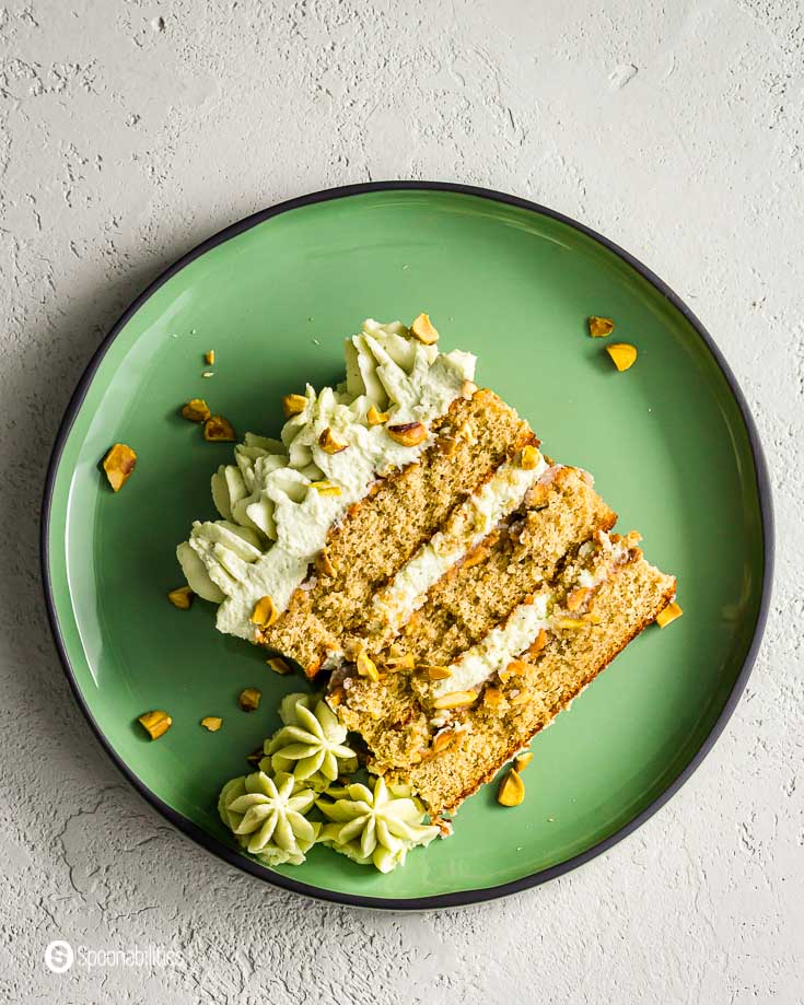 Round green plate with a slice of pistachio tiramisu cake with chopped pistachios. Recipe at Spoonabilities.com