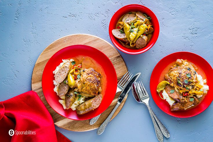 overhead photo with three red plates with mashed potatoes, chicken, Italian sausages, veggies and Greek Green (mild pepperoncini) Peppers. Recipe at Spoonabilities.com