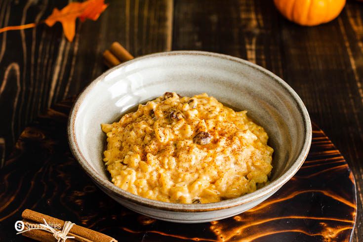 A light brown-grey bowl with pumpkin rice pudding with coconut milk, Vermont maple syrup, and pumpkin pie spice. recipe at Spoonabilities.com