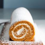 A close-up photo with the beautiful end of the roll cake shows the spiral form filled with sweet cream cheese filling. Recipe at Spoonabilities.com